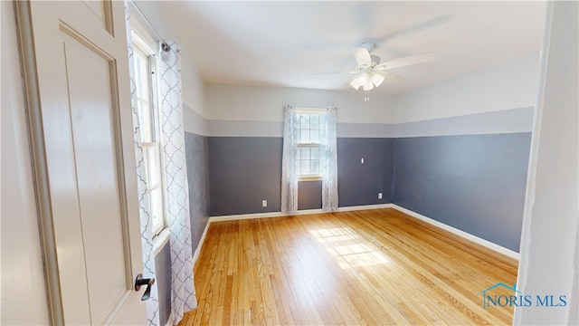 empty room featuring a ceiling fan, baseboards, and hardwood / wood-style floors