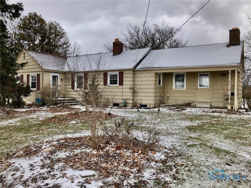 snow covered rear of property featuring a chimney