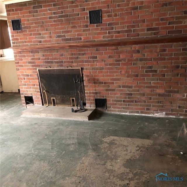 interior details featuring unfinished concrete floors, a brick fireplace, and visible vents