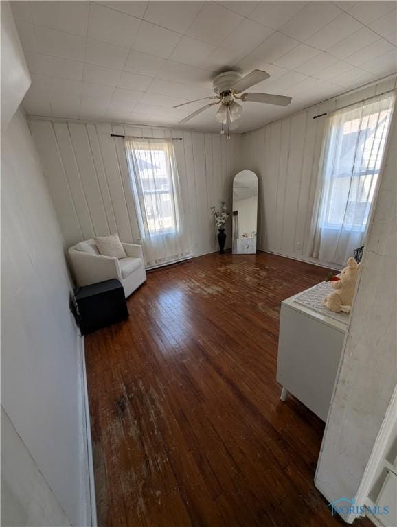 unfurnished room featuring hardwood / wood-style flooring, a ceiling fan, and arched walkways