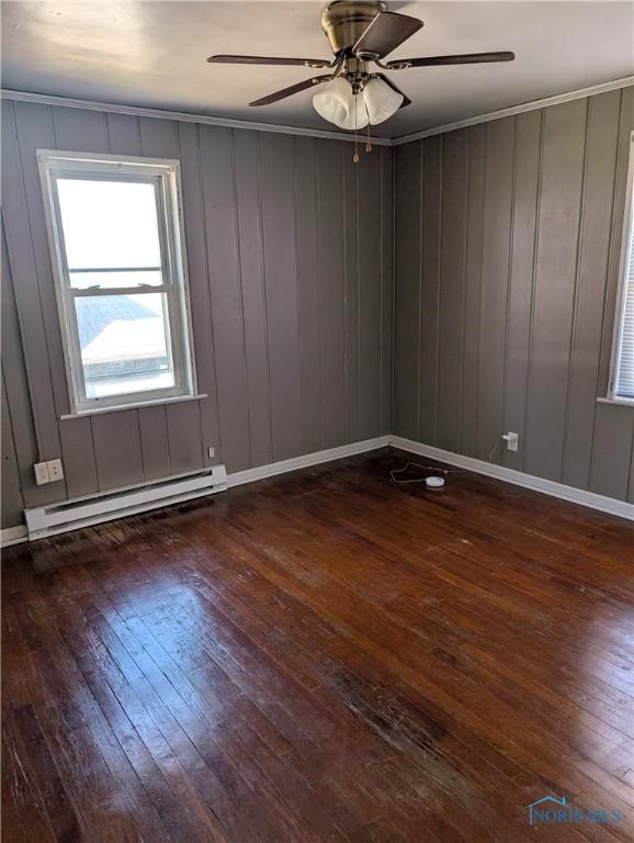 empty room with a baseboard radiator, wood-type flooring, baseboards, and ceiling fan