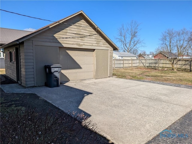 detached garage featuring driveway and fence