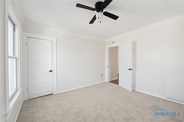 unfurnished bedroom featuring multiple windows, baseboards, carpet, and a ceiling fan