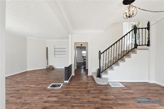 entryway featuring visible vents, a textured ceiling, wood finished floors, baseboards, and stairs