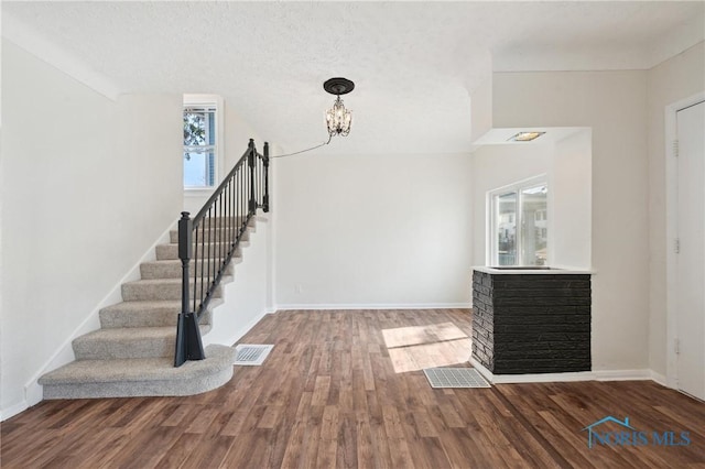 entryway with visible vents, a notable chandelier, wood finished floors, stairway, and baseboards