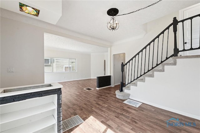 foyer entrance with visible vents, wood finished floors, stairway, an inviting chandelier, and baseboards