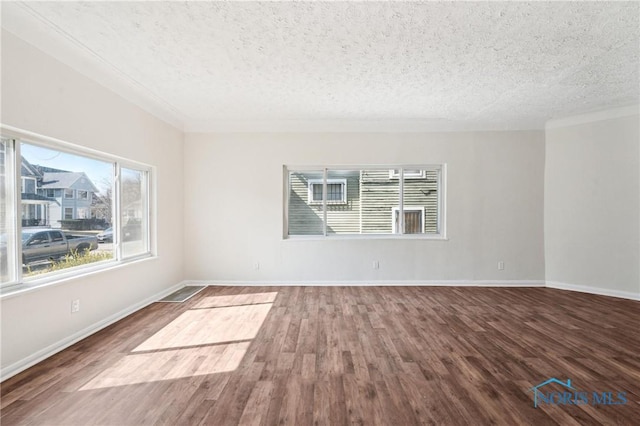 empty room featuring baseboards, a textured ceiling, and wood finished floors