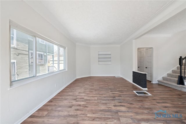 unfurnished room with crown molding, stairs, baseboards, and wood finished floors