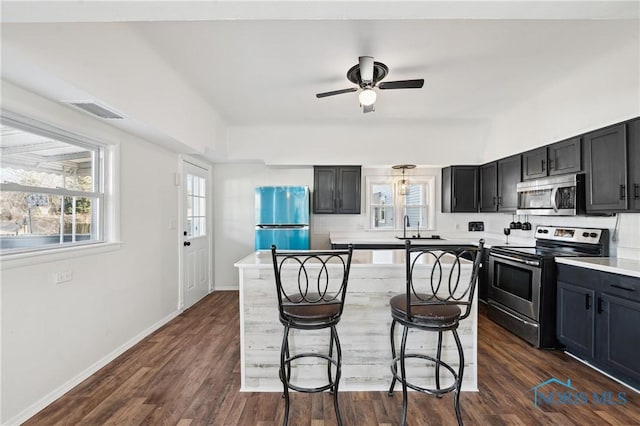 kitchen with visible vents, dark wood finished floors, a breakfast bar, stainless steel appliances, and a sink