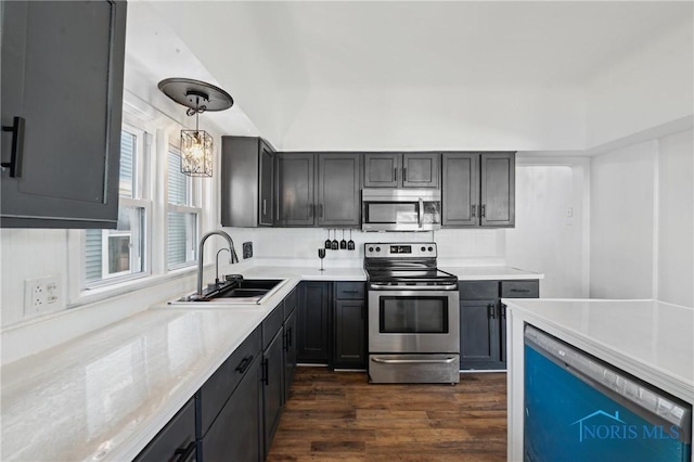 kitchen featuring dark wood-type flooring, pendant lighting, a sink, appliances with stainless steel finishes, and light countertops