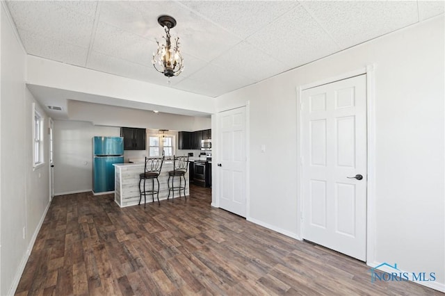 kitchen featuring a breakfast bar area, light countertops, dark wood-type flooring, appliances with stainless steel finishes, and a chandelier