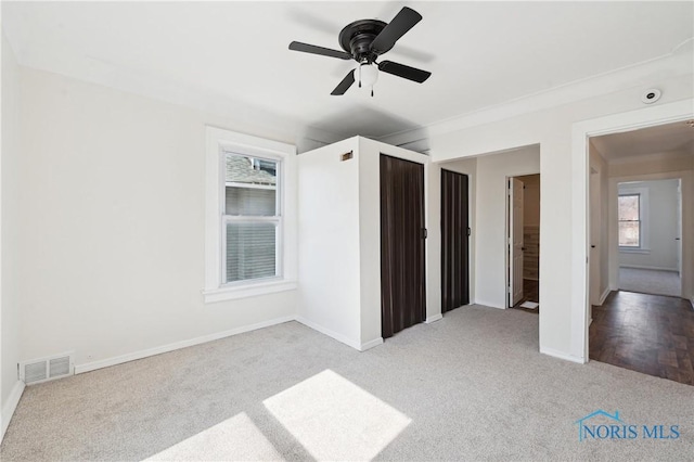 unfurnished bedroom featuring visible vents, baseboards, light colored carpet, and a ceiling fan