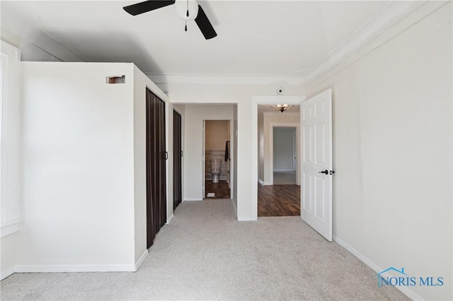 interior space with carpet flooring, a ceiling fan, and baseboards