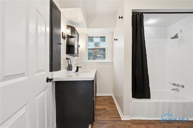 bathroom featuring vanity, shower / bathtub combination with curtain, wood finished floors, and baseboards