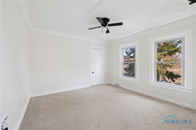 carpeted spare room featuring baseboards, visible vents, and ceiling fan