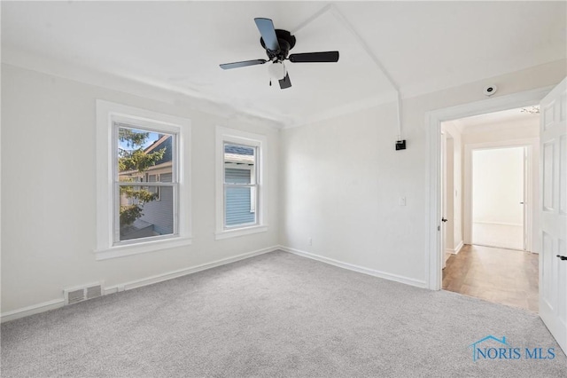 carpeted empty room featuring visible vents, baseboards, and a ceiling fan