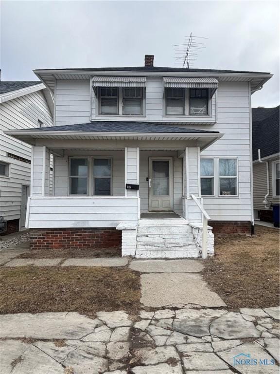 view of front facade with covered porch and a chimney