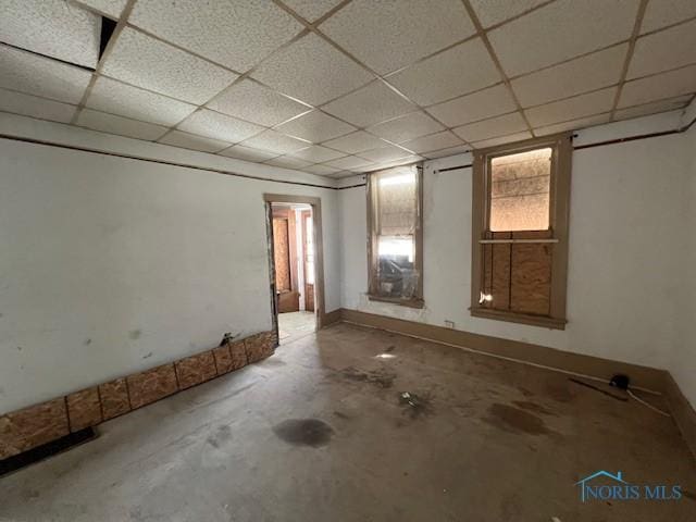 below grade area with a paneled ceiling and baseboards