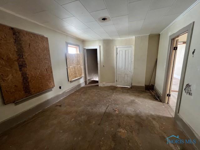 interior space with crown molding, unfinished concrete floors, and baseboards