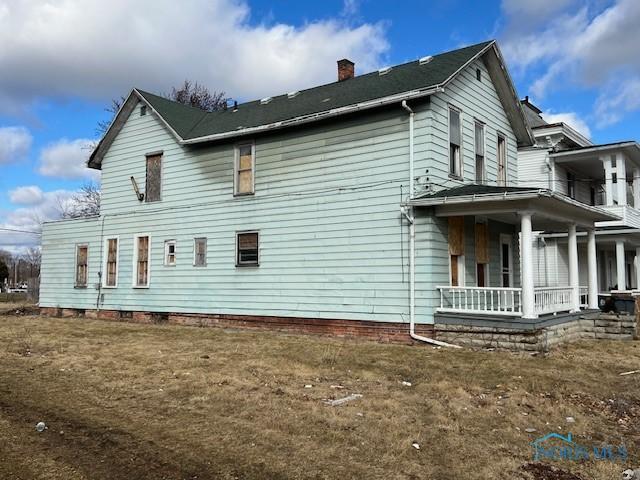 view of side of property with a porch and a chimney