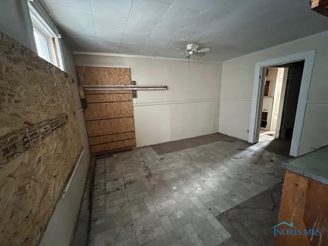 interior space with tile patterned floors, a ceiling fan, and ornamental molding