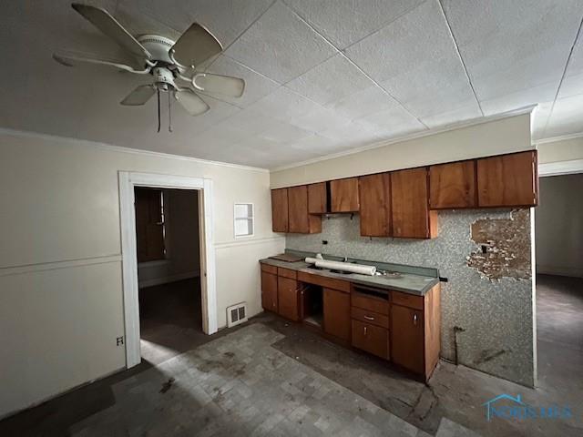 kitchen featuring visible vents, ornamental molding, backsplash, brown cabinetry, and ceiling fan