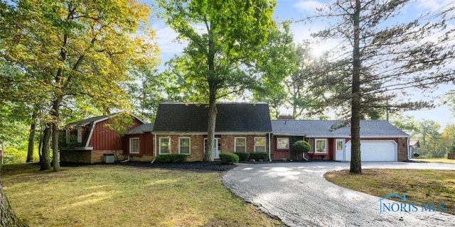 view of front facade with aphalt driveway, a garage, brick siding, and a front yard