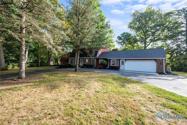 single story home featuring a front yard, driveway, a chimney, a garage, and brick siding