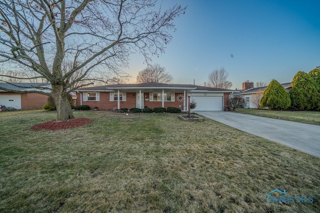 ranch-style home featuring brick siding, an attached garage, driveway, and a front yard