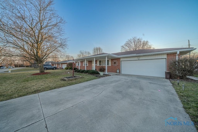 ranch-style house with a front lawn, an attached garage, brick siding, and driveway