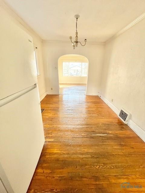 unfurnished dining area featuring baseboards, wood finished floors, visible vents, and ornamental molding