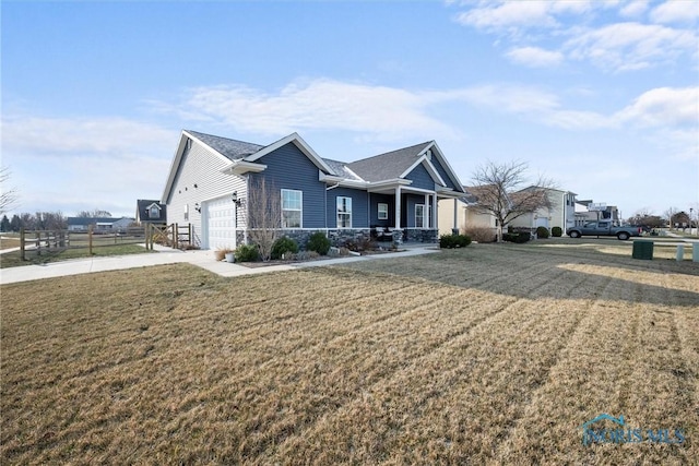 view of front of property featuring fence, concrete driveway, a front yard, a garage, and stone siding