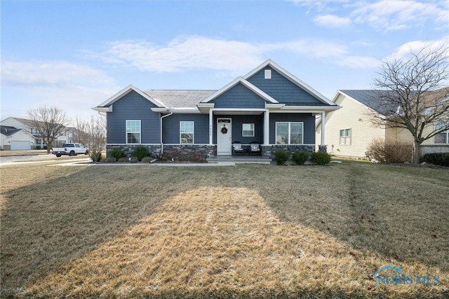 craftsman house with stone siding, a porch, and a front yard