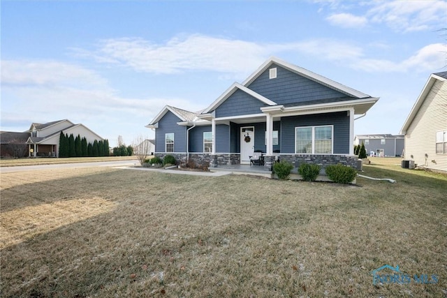 craftsman house featuring a front lawn, stone siding, and central AC