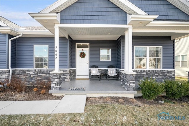 entrance to property featuring covered porch and stone siding