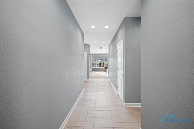 hall with wood tiled floor, recessed lighting, baseboards, and a textured wall