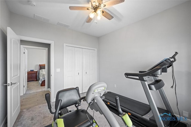 workout area with light colored carpet, a ceiling fan, visible vents, and baseboards