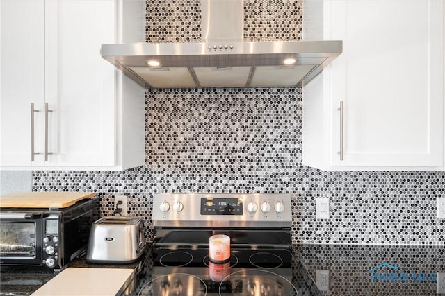 kitchen featuring white cabinetry, tasteful backsplash, stainless steel electric range, and wall chimney range hood