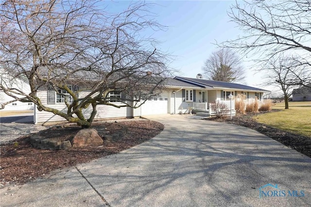 ranch-style house with a porch, concrete driveway, and a garage