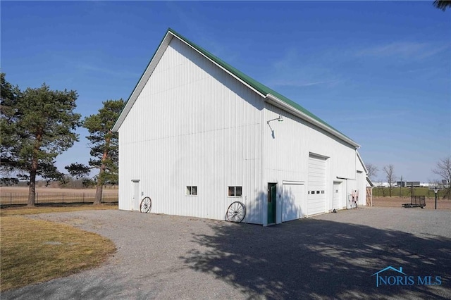 exterior space featuring a pole building, a detached garage, fence, and an outdoor structure