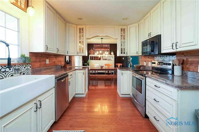 kitchen featuring white cabinetry, glass insert cabinets, light wood-style floors, and stainless steel appliances