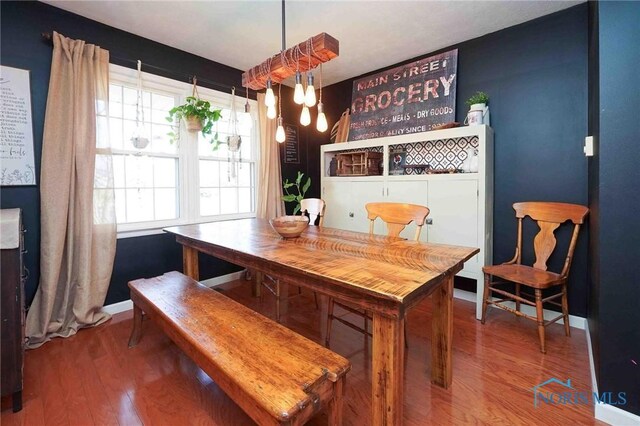 dining space with baseboards and wood finished floors