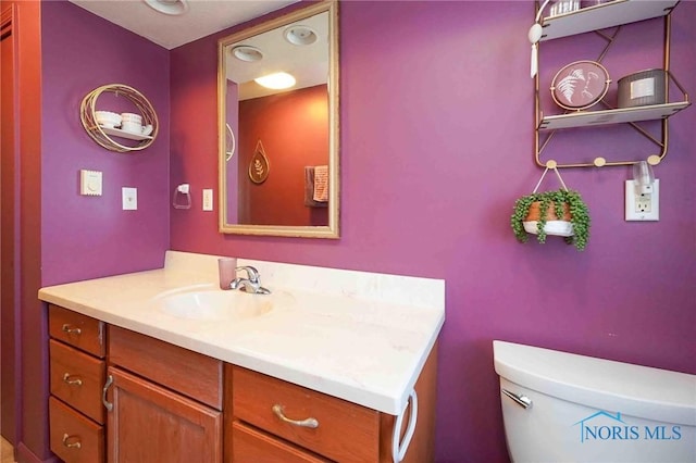 half bath featuring vanity and toilet