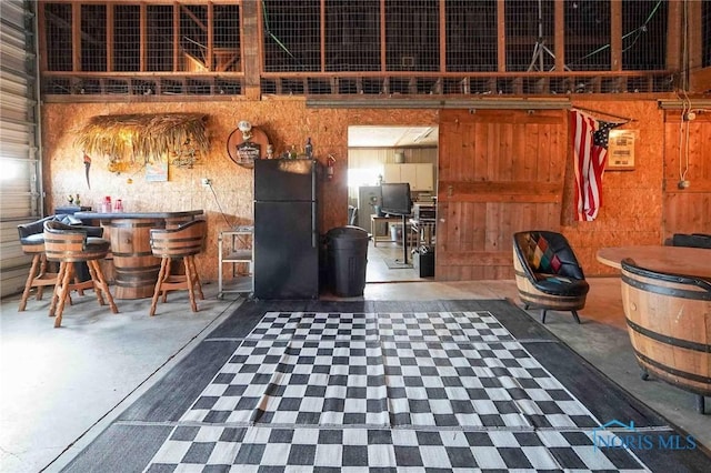 interior space featuring wooden walls, a bar, concrete flooring, and a towering ceiling