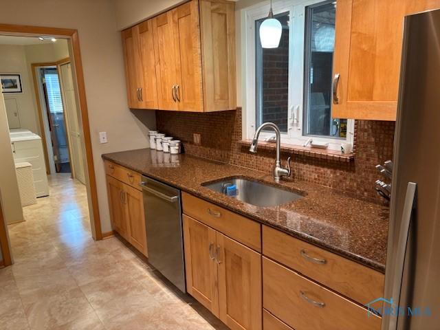 kitchen featuring a sink, brown cabinets, appliances with stainless steel finishes, and dark stone countertops