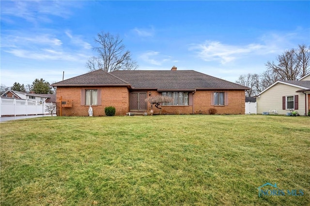 back of property featuring a lawn, fence, a shingled roof, brick siding, and a chimney