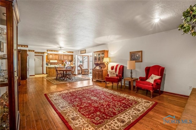 living room featuring hardwood / wood-style floors, baseboards, and a textured ceiling