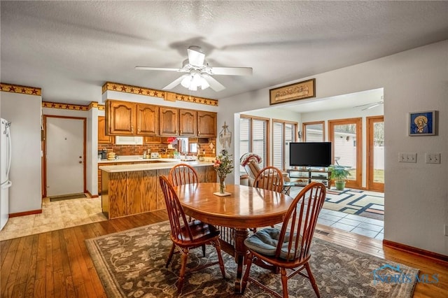 dining room with baseboards, a textured ceiling, a ceiling fan, and hardwood / wood-style floors