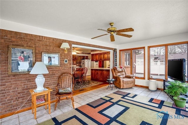 living area with light tile patterned floors, brick wall, and ceiling fan