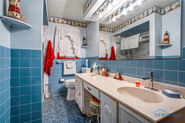 full bathroom featuring a sink, toilet, tile walls, and double vanity